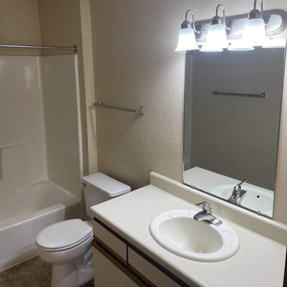 a bathroom with a toilet, sink, and mirror.