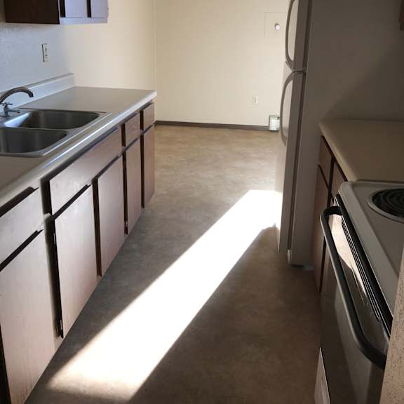 a kitchen with a sink, refrigerator, and cabinets.