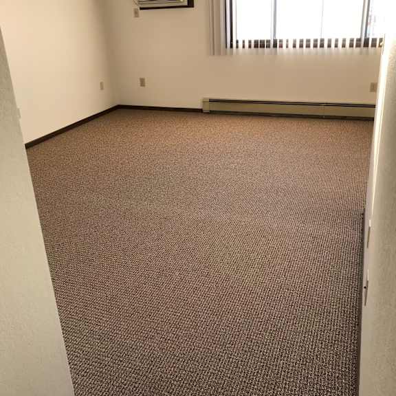 a room with a carpeted floor and a window with blinds.