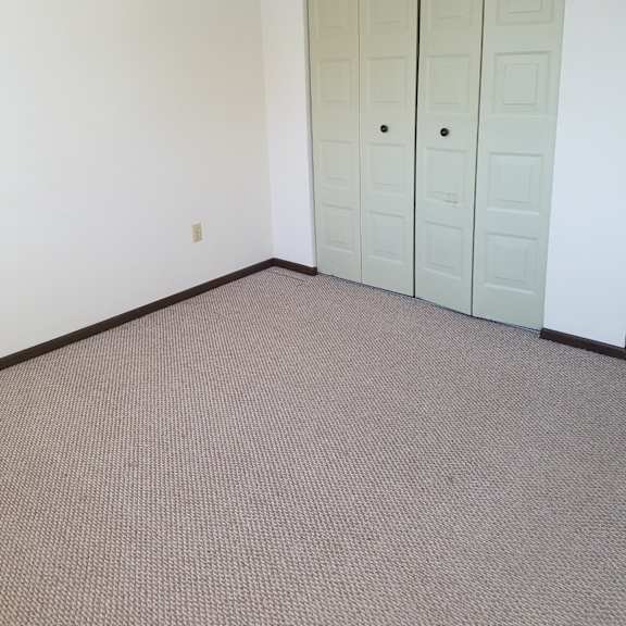 a room with a white wall and a brown carpet.