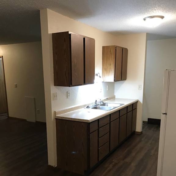 a kitchen with dark wood floors and white walls.