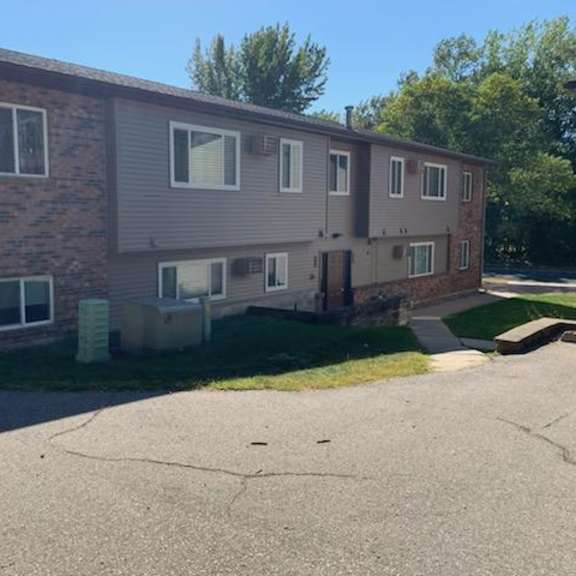 apartment building with a parking lot in front.