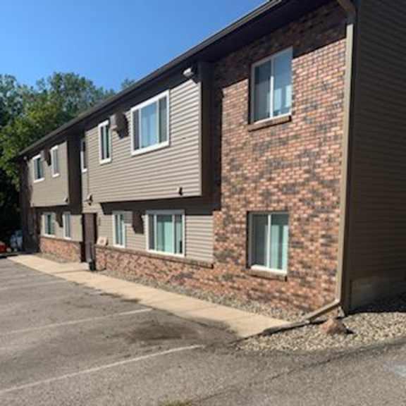 a brick building with a parking lot in front.