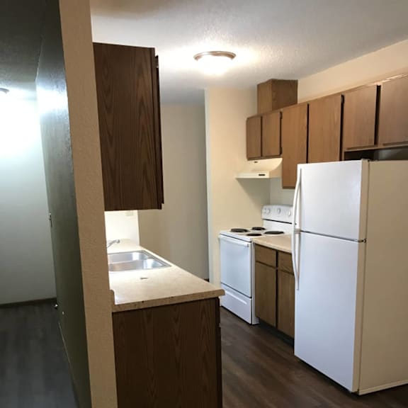 a kitchen with a white fridge and wooden cabinets.