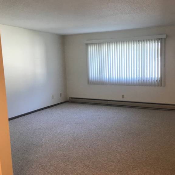 a room with a window covered by blinds and a small tv mounted on the wall.