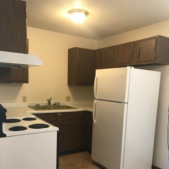 a white refrigerator stands in a kitchen with brown cabinets.