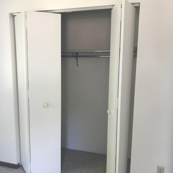 a white closet with a door open and a coat hanger inside.