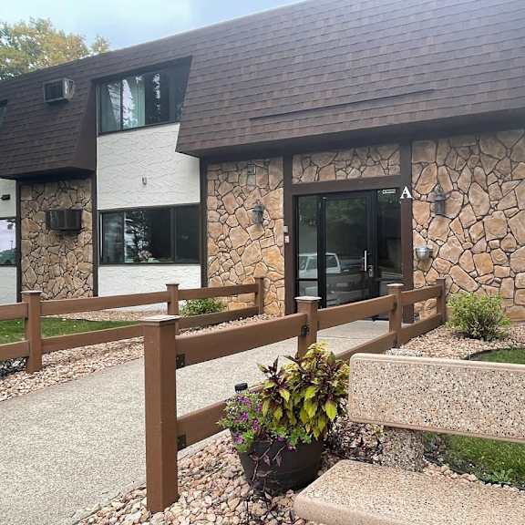 a modern house with a stone wall and a wooden fence.