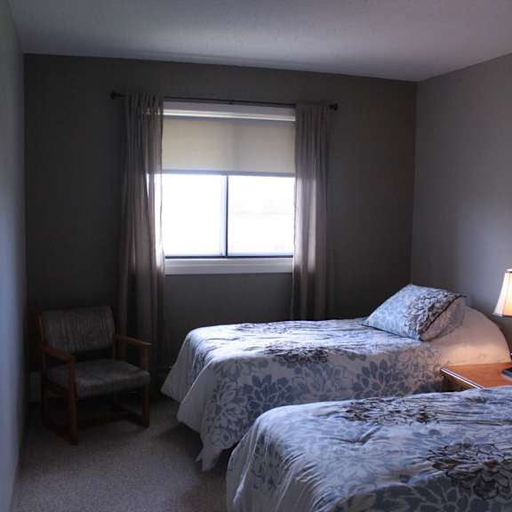 two twin beds with blue bedspreads in a small room with a window.