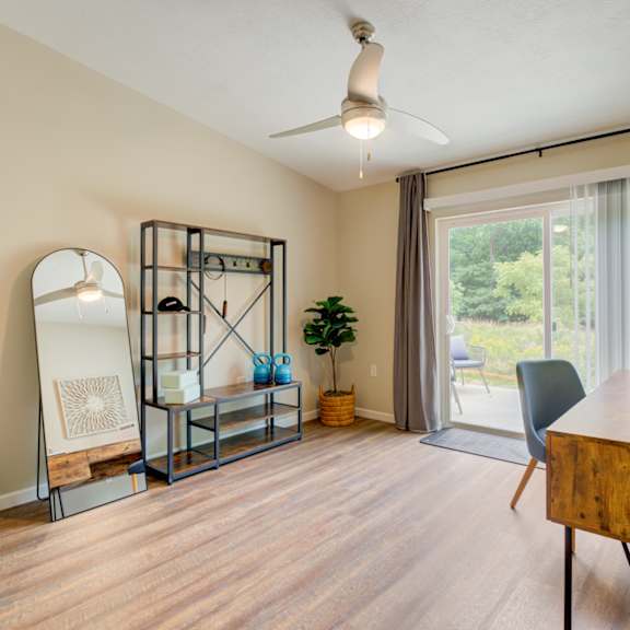 a living room with a desk and a sliding glass door
