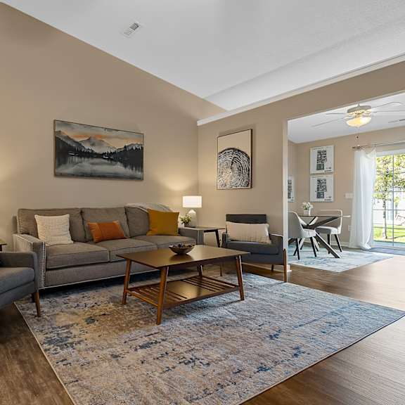a living room with a grey couch, a wooden coffee table, and a painting on the wall.