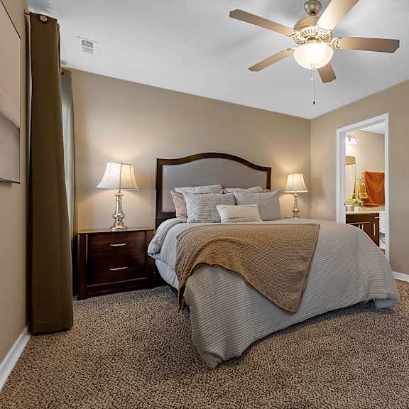 a bedroom with a bed, two lamps, and a ceiling fan.