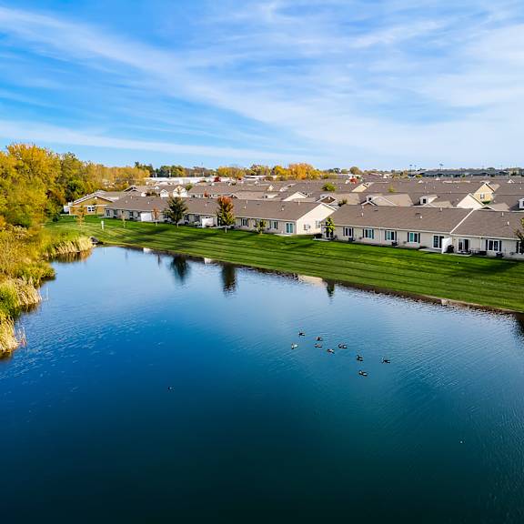 a serene lake in front of a residential area with houses and trees.