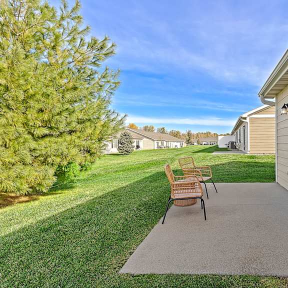 a patio with a bench and a tree in the background.