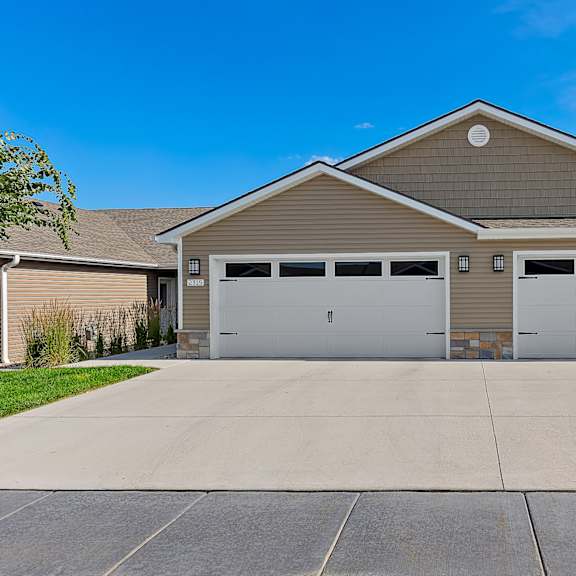 a two-car garage with a tan house in the background.