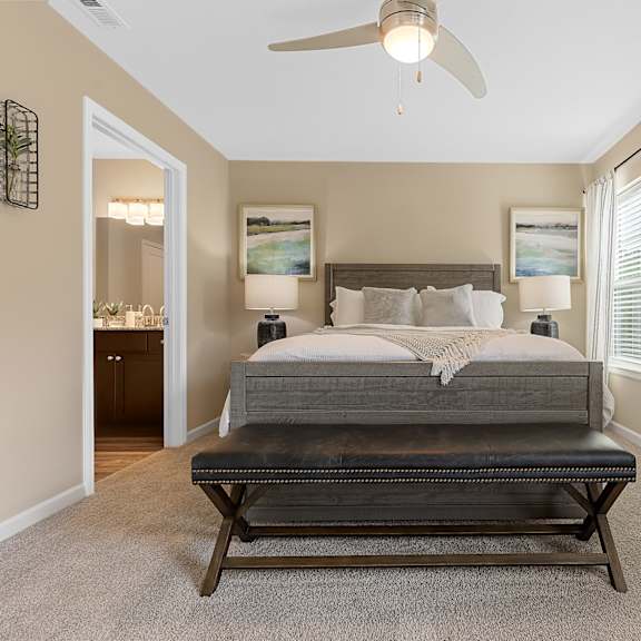a bedroom with a bed, a ceiling fan, and a painting on the wall.