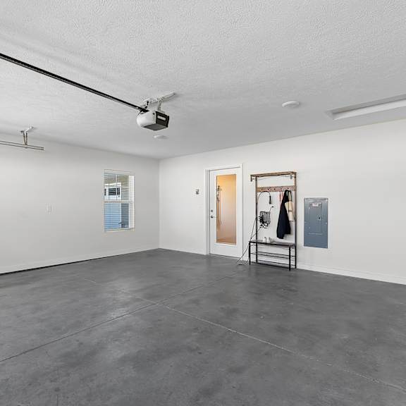 a room with a grey floor and white walls has a door and a painting on the wall.