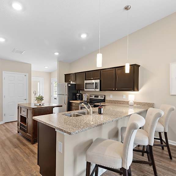 a kitchen with a granite countertop and white chairs.