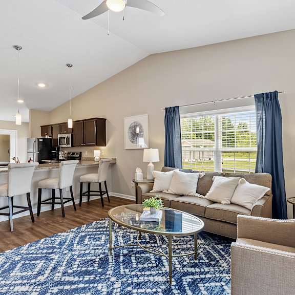 a living room with a blue rug and a glass coffee table.