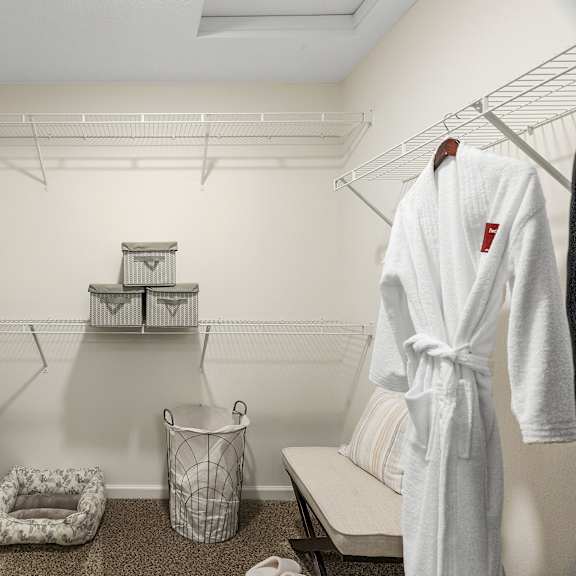 a white bathrobe is hanging on a rack in a small, white bathroom.
