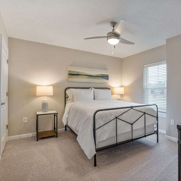 a bedroom with a bed, nightstands, and a ceiling fan.