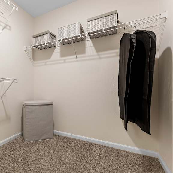 a walk-in closet with a coat hanging on the hook.