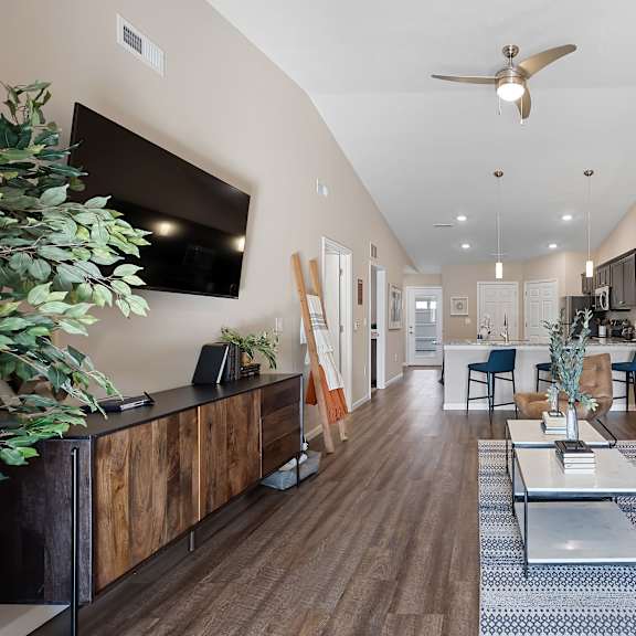 a living room with a white couch, a wooden cabinet, and a ceiling fan.