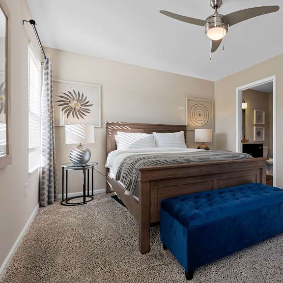 a bedroom with a bed, a bench, and a ceiling fan.