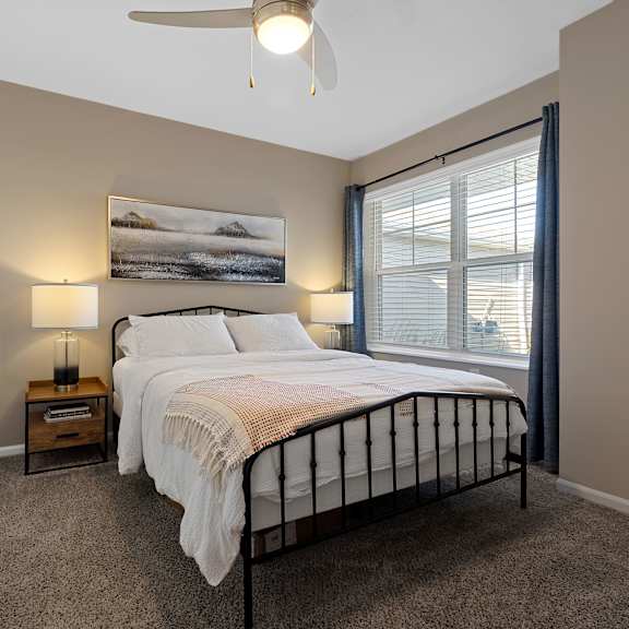 a bedroom with a large bed, a ceiling fan, and a painting on the wall.