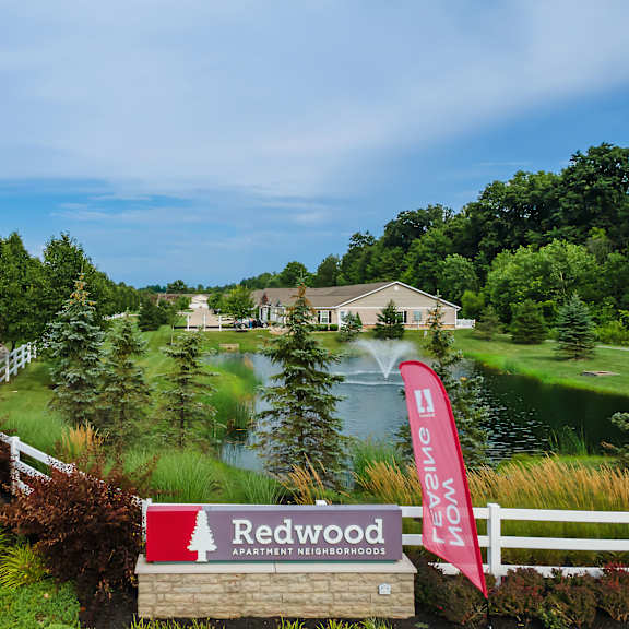 a sign for redwood apartment neighborhoods is in front of a pond.