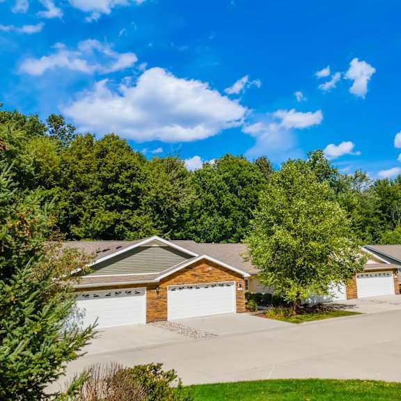 a house with a driveway and garage is surrounded by trees.