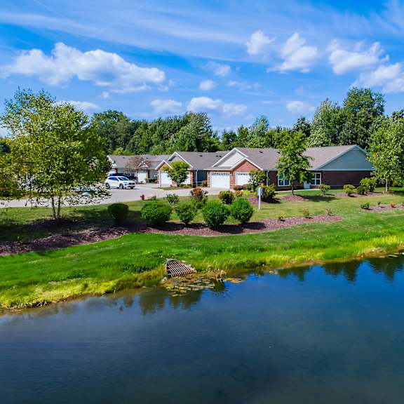 a serene lakeside view with a house and trees in the background.