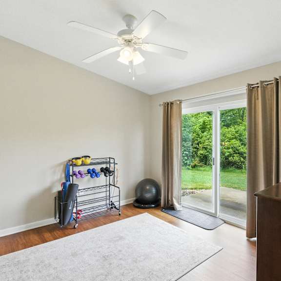 a room with a ceiling fan, a rug, a window with curtains, and a wooden cabinet.