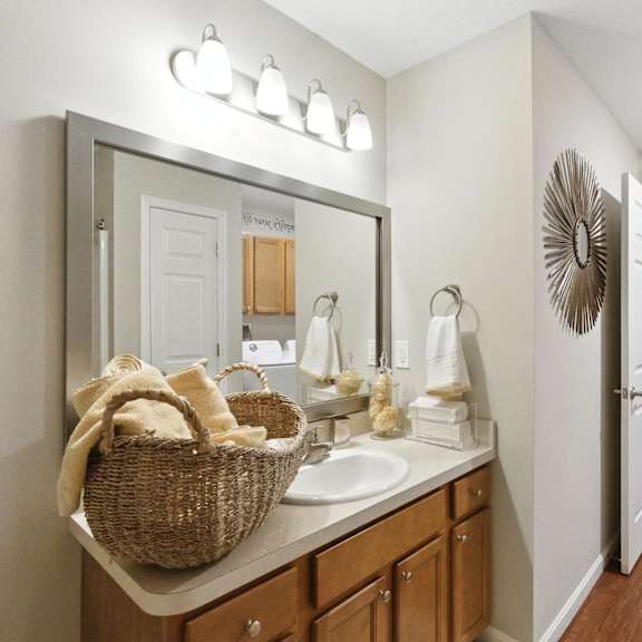 a bathroom with a mirror, sink, and a basket of towels.