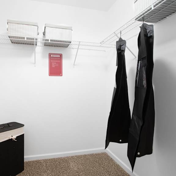 a small closet with a red sign on the wall and two coats hanging up.