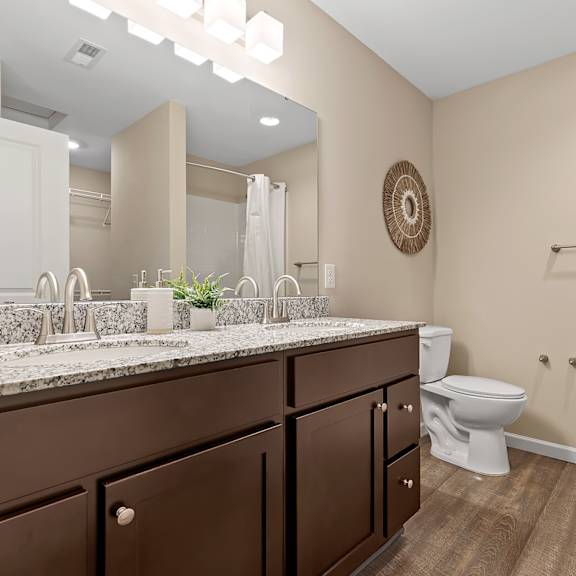a bathroom with brown cabinets and a marble countertop.