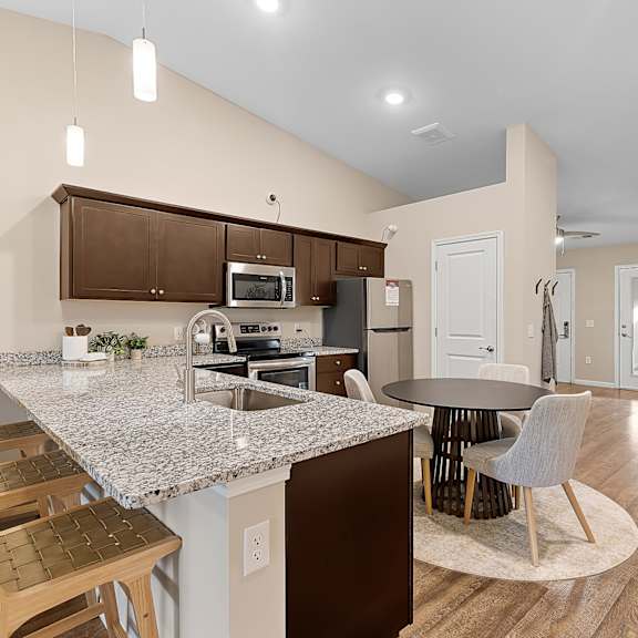 a kitchen with a granite countertop and wooden chairs.