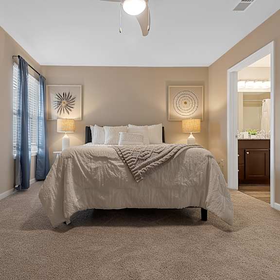 a bedroom with a bed, two wall lamps, and a ceiling fan.