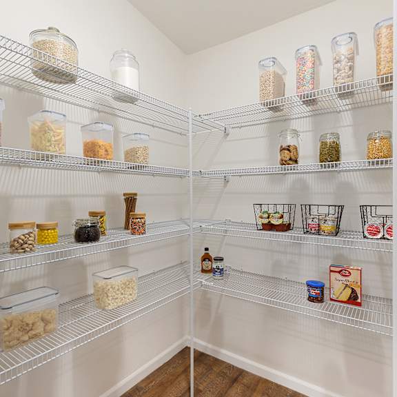 a pantry with a white door and shelves filled with jars and containers.