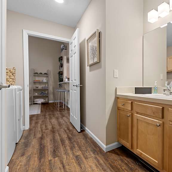 a bathroom with a wooden vanity and a white fridge.