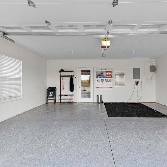a spacious garage with a black mat on the floor and a red sign on the door.