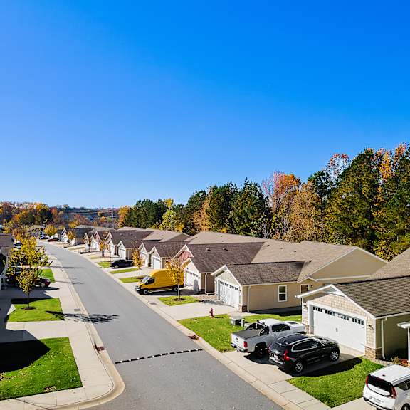 a residential street with houses on both sides and cars parked in front.