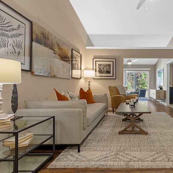 a living room with a glass coffee table and a white couch.