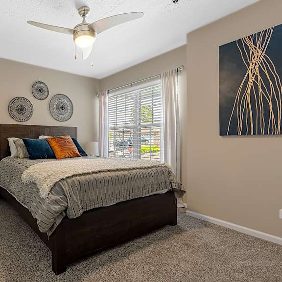 a bedroom with a bed, a ceiling fan, and a window with blinds.