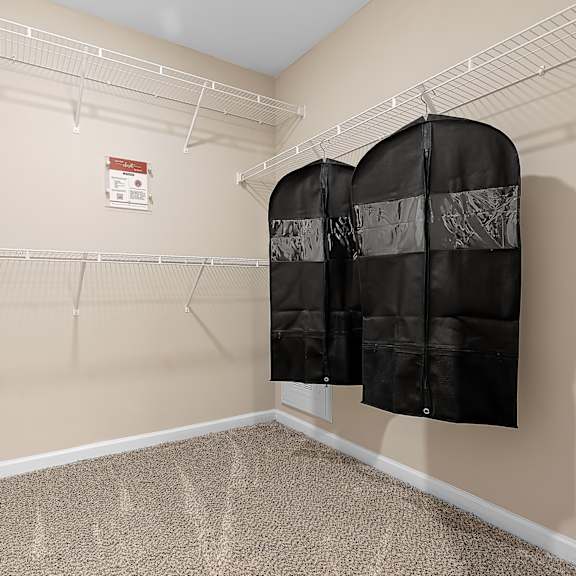 a room with a carpeted floor and a white door, with two black hanging storage units.