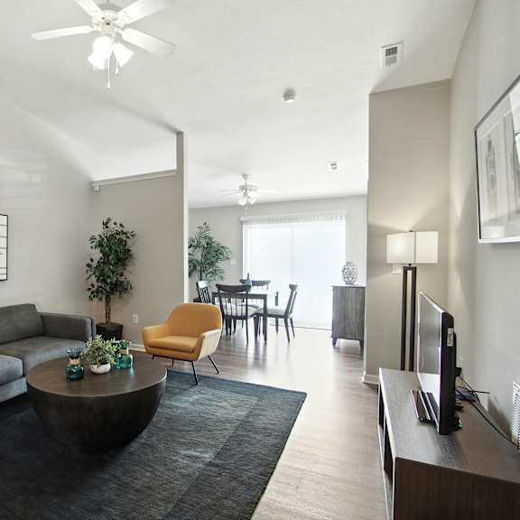 a living room with a grey couch, a yellow chair, a black coffee table, and a painting on the wall.