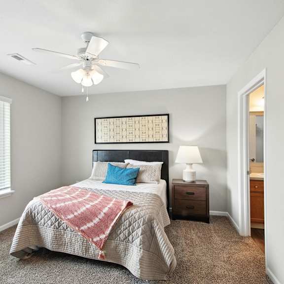 a bedroom with a bed, a ceiling fan, and a window with blinds.