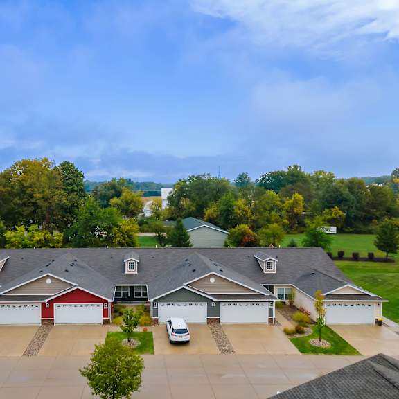 a large house with a red garage door is surrounded by a driveway and trees.