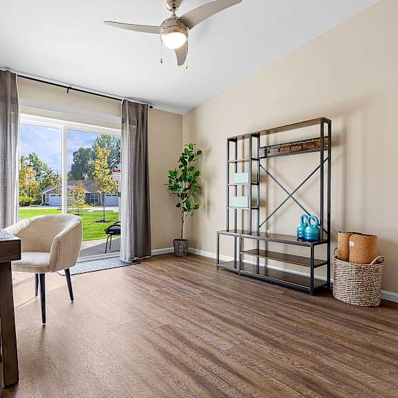 a room with a wooden table and a white chair with a view of the backyard through the window.