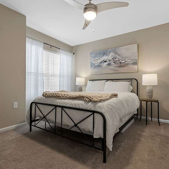 a bedroom with a bed, a ceiling fan, and a painting on the wall.